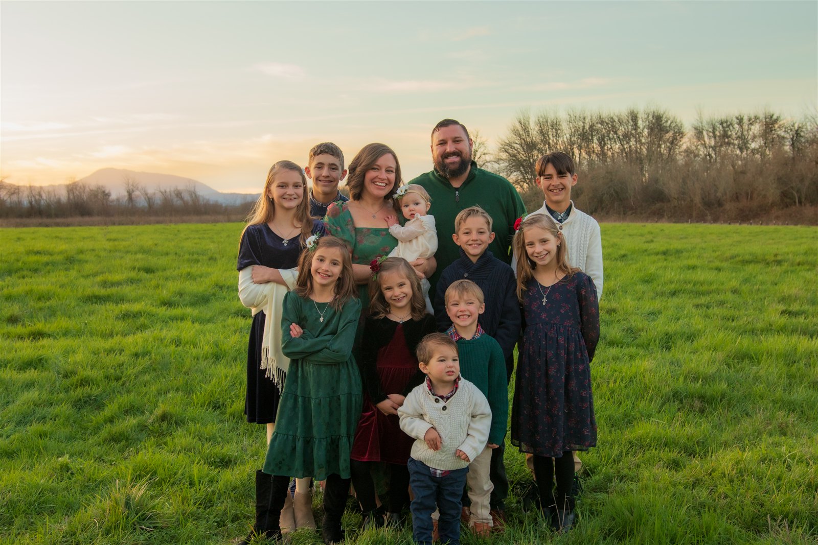 Stephanie and her family together in a green field at sunset
